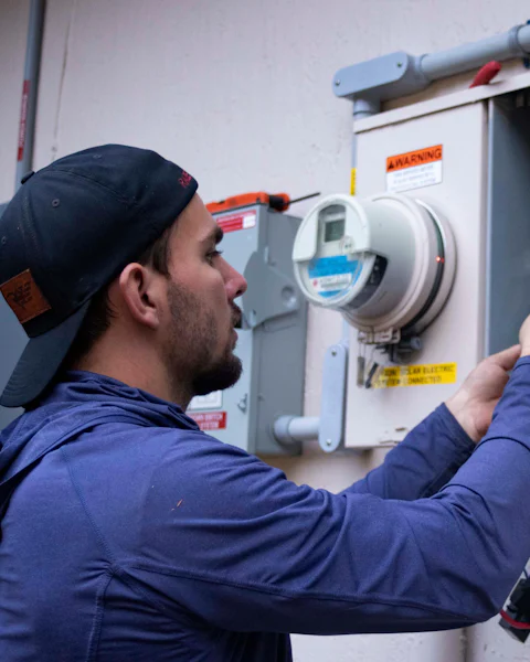An electrician working inside a service panel